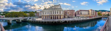 Bilbao şehir manzarası, Arriaga Tiyatrosu ve sakin Nervion Nehri boyunca uzanan tarihi binalar bulutlu bir gökyüzü üzerindedir. Bilbao İspanya 20 Ekim 2025