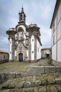 Barok kilisesinin ön cephesini taş detaylar ve antik çan kulesiyle süslemek, geleneksel bir Avrupa köyünün kaldırım taşlı avlusunda dikilmek, tarihi dini mimariyi temsil etmek.