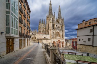 Burgos Katedralleri Gotik cepheyi süslüyor ve dramatik bulutların altında dar bir şehir caddesinde yükselen kuleler, UNESCO 'nun tarihi simgesinin tarihi taş detaylarını gözler önüne seriyor.