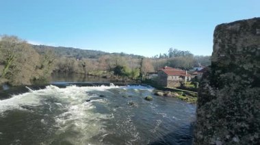 Tambre Nehri 'nin Galiçya' daki Maceira köyünden akan manzarası, eski taş evler ve güneşli bir günün yer aldığı Camino de Santiago 'daki hacılar için önemli bir nokta.
