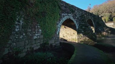 İspanya 'nın Galiçya kentindeki Tamber nehri üzerindeki tarihi Ponte Maceira, parlak güneşli bir günde Camino de Santiago boyunca seyahat eden hacılar için önemli bir geçiş noktası.