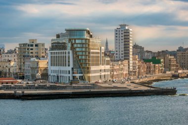 Havana şehrinin ufuk çizgisi tarihi binalarla birlikte modern Grand Packard Hotel 'i gösteriyor. İkonik Malecon güvertesi boyunca uzanan Karayip Denizi önplanda bulutlu bir gökyüzünün altında