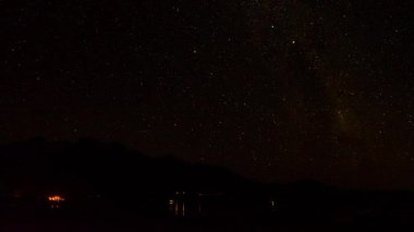 Glenorchy, Yeni Zelanda yakınlarındaki karanlık dağ sırtında yıldızlarla dolu berrak bir gece gölü..