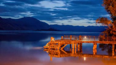 Glenorchy rıhtımının akşam vakti Yeni Zelanda, Wakatipu Gölü 'ndeki yumuşak ışık yansımaları ve gün ışığının geceye karışması..