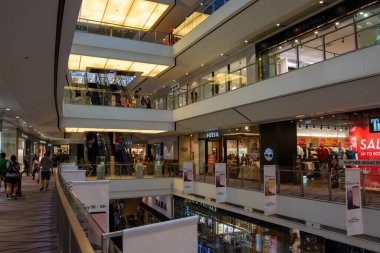 Çeşitli perakende mağazaları, yürüyen merdivenleri ve alışveriş merkezlerinin bulunduğu çeşitli katları olan modern bir alışveriş merkezi.