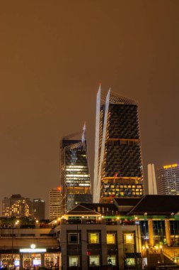 Eşsiz mimari tasarımı olan modern gökdelenlerin gece görüşü, karanlık gökyüzüne karşı aydınlatılmış binalar, şehir manzarası