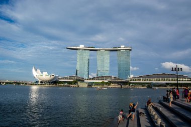 Singapur 'daki marina körfezi kumları ve sanat müzesinin manzarası. Önünde açık mavi bir gökyüzü ve su var.