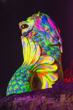 Gece parlak renkli bir aslan heykeli, parlak desenler ve renkler sergiliyor.