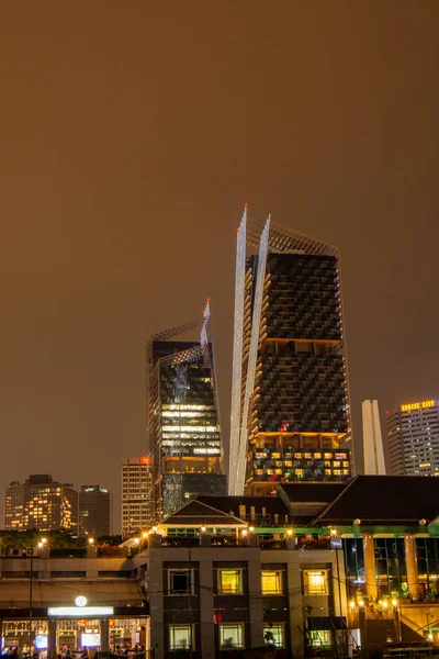 Eşsiz mimari tasarımı olan modern gökdelenlerin gece görüşü, karanlık gökyüzüne karşı aydınlatılmış binalar, şehir manzarası