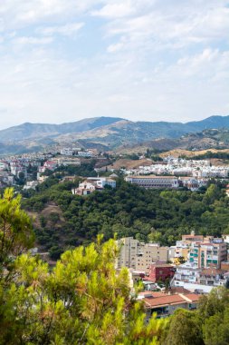 Scenic view of a hilly landscape with buildings and lush greenery.