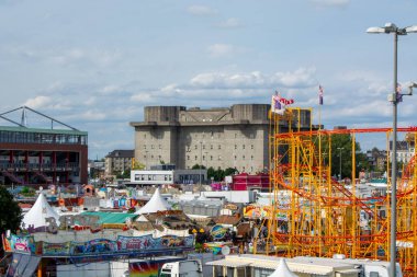 Lunapark sahnesi, lunapark treni, çadır ve çeşitli tezgahlar gibi renkli çekimler büyük, benzersiz bir binanın arka planına karşı kuruludur.