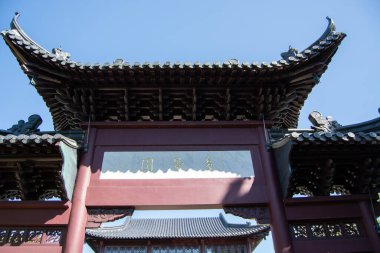 A traditional Chinese architectural structure with ornate roof details and decorative elements, set against a clear blue sky