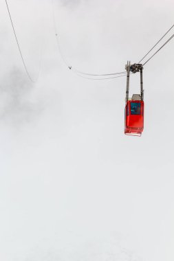 Beyaz siste kırmızı teleferik kayboldu. Kötü havada turistleri Lomnicky Tepesi 'ne taşıyan teleferik. Fotoğraf kışın High Tatras, Slovakya 'da çekildi.