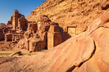 Petra, Jordan. Sıcak güneşli bir günde Ürdün 'ün Petra kentinin antik harabelerinin manzarası. UNESCO Dünya Mirası Alanı. Ünlü arkeolojik mekan ve turistik mekan. Önplandaki kumtaşının yapısını kapat.