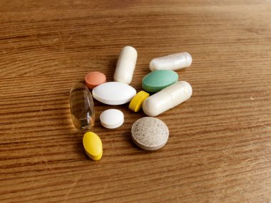 Çeşitli ilaç kapsülleri, haplar, tabletler, vitaminler, ahşap masadaki takviyeler. Sağlık hizmetleri kavramları. Farmakolojik hazırlıklar, tıbbi ürünler