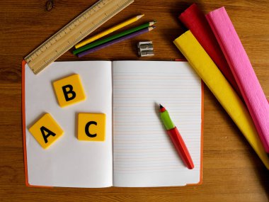 Tahta Masa 'da Not Defteri ve Kırtasiye ile Öğrenim Malzemeleri Sergilendi. Okul konseptine geri dönelim. Üst görünüm, düz uzanma