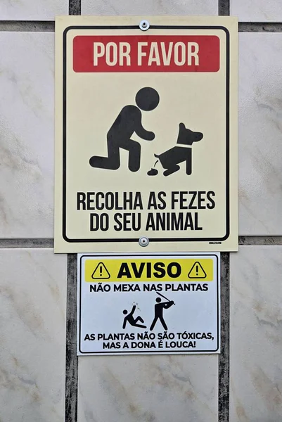 Dış duvarda Portekizce yazılmış iki tabela var: biri hayvan sahiplerinden evcil hayvanlarının dışkılarını toplamalarını istiyor, diğeri bitkiler hakkında uyarıda bulunuyor; hayvan bakımını doğaya bağlayan açık ve eğlenceli bir mesaj.