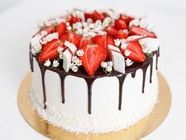 Taart is versierd met verse aardbeien en bloemen en chocolade close-up — Stockfoto