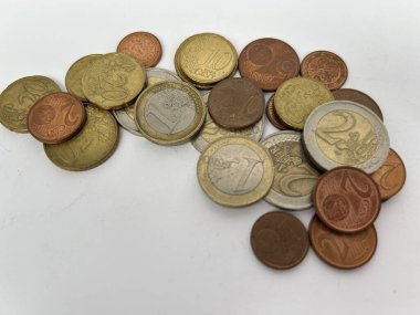 Beyaz bir yüzeye saçılmış karışık avro sikkeleri koleksiyonu. Görüntü bakır gümüş ve altın tonlarını da içeren çeşitli metalik renkleri gösteriyor. Kompozisyon vurgulanıyor