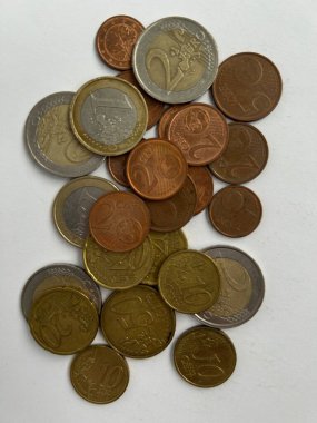 Beyaz bir yüzeye saçılmış karışık avro sikkeleri koleksiyonu. Görüntü bakır gümüş ve altın tonlarını da içeren çeşitli metalik renkleri gösteriyor. Kompozisyon vurgulanıyor