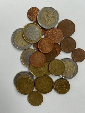 Beyaz bir yüzeye saçılmış karışık avro sikkeleri koleksiyonu. Görüntü bakır gümüş ve altın tonlarını da içeren çeşitli metalik renkleri gösteriyor. Kompozisyon vurgulanıyor