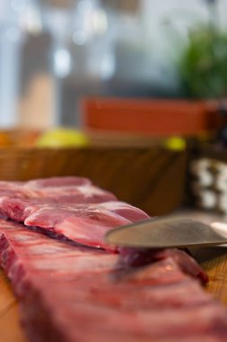 Kesme tahtasında çiğ domuz kaburgası, yemek pişirmek için et hazırlayan bıçak.