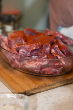 Kesme tahtasındaki cam bir tabakta çiğ domuz kaburgası, kırmızı biber soslu.
