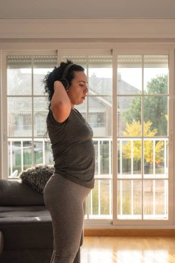 Evde spor salonuna hazırlanırken kulaklıkları ayarlayan kadın.