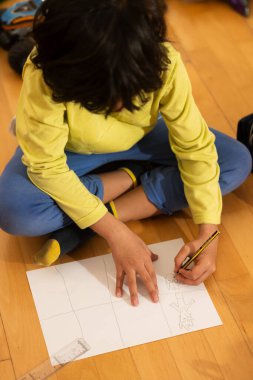 Kağıt üzerinde kalemle çizen küçük çocuk, yaratıcılık ve sanatsal becerileri geliştiriyor.