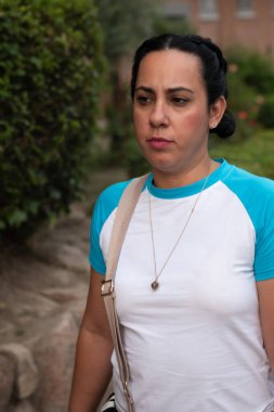 Kadın dışarıda omuz çantasıyla yürüyor, düşünceli ve ciddi görünüyor.