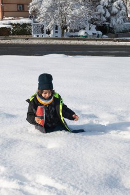 Çocuk derin bir kar yağışı altında oturuyor, cips yiyor.