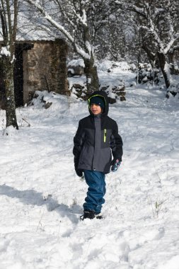 Karlı bir arazide kış havasının tadını çıkaran bir çocuk.