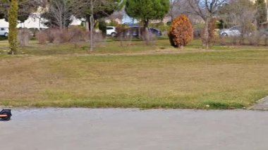 Çocuk kaskını takıyor ve güneşli bir günde şehir parkında modern elektrikli scooter kullanıyor.