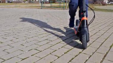 Halka açık bir parkta elektrikli scooter kullanan birinin düşük açılı görüntüsü.