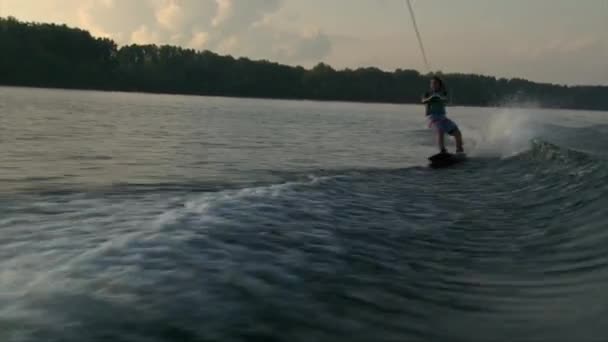 Meisje op wakeboard raken het water wave, donkere zomer — Stockvideo