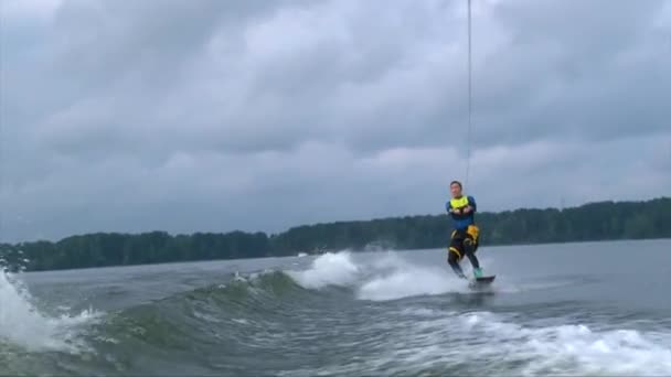 Un jeune homme asiatique saute le sillage derrière un bateau — Video