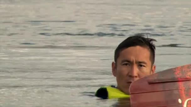 Primer plano disparo wakeboarder asiático hombre cara flotando en agua lago con wake board — Vídeos de Stock