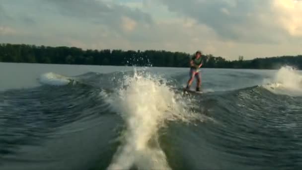 Wakeboarder dívka dělat vlny na vlnu trik na rybníku vodu, golden sunset — Stock video