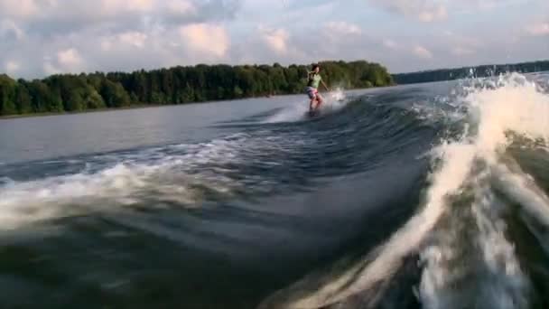 Κορίτσι με wakeboard πίσω από τη βάρκα, ηλιοβασίλεμα — Αρχείο Βίντεο