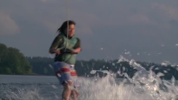 Крупним планом знімок дівчини на вейкборді стрибає хвилю за човном — стокове відео