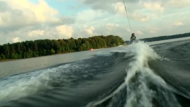 Jonge vrouw wake boarding achter de motorboot — Stockvideo