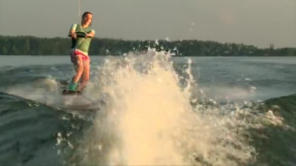 Wakeboarder chica saltar las olas en el agua del lago, puesta de sol de verano — Vídeo de stock