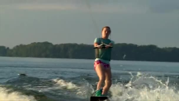 Štíhlé dospívající dívka na wakeboard, západu slunce na obloze — Stock video