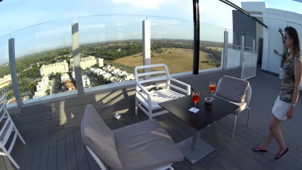 Mädchen in Sonnenbrille und Minirock kommen und sitzen auf der Terrasse am Tisch — Stockvideo