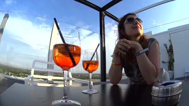 Chica en gafas de sol beber cóctel, sentado en la terraza en la azotea sky bar — Vídeo de stock