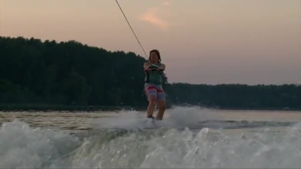 Wakeboarder meisje sterren rijden van meerwater op zonsondergang — Stockvideo