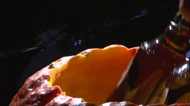 Put bottle beer  and ice cubes inside Halloween pumpkin jack o lantern and ice — Stock Video