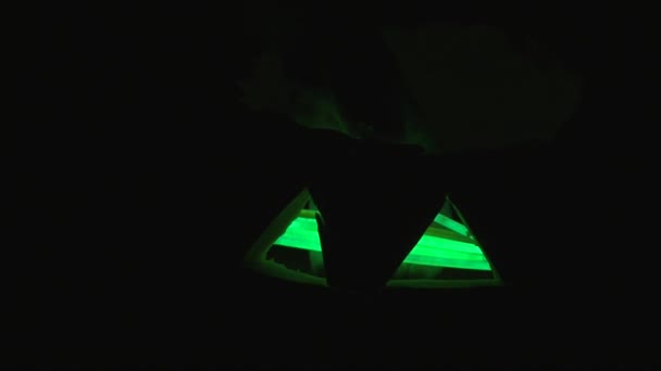 Рука в темноте с зелеными светящимися палками в Хэллоуин тыква — стоковое видео