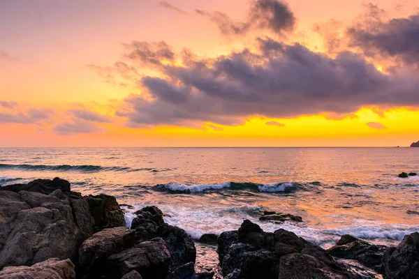 Yazın denizde gün doğumu. Sahilde, ufukta sıcak bir sabah gökyüzü parıltısıyla. Sakin deniz manzaralı sakin dalgalar tatil için arka planda. Bulutların arkasındaki güneş