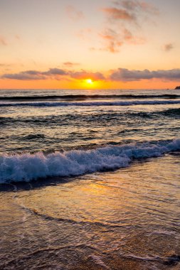 Golden Sunrise 'da kumlu sahilde dalgaların yaklaşması. Yazın Karadeniz 'de sozopol dolu sıcak bambu plajı. Güneş ufukta parlıyordu. seyahat arkaplanı için güzel düşük açılı dikey resim